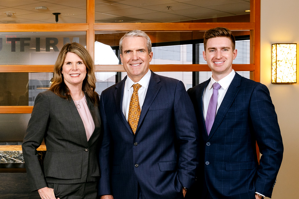 Attorneys Pamela Liosi-Traut, Eric V. Traut and Connor J. Traut in front of conference room.