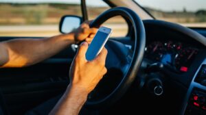 Man driving car while looking at his cell phone.