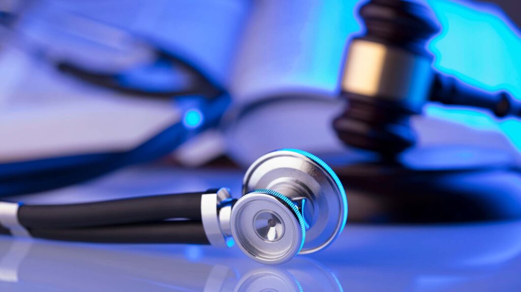 Stethoscope on table with gavel behind it.